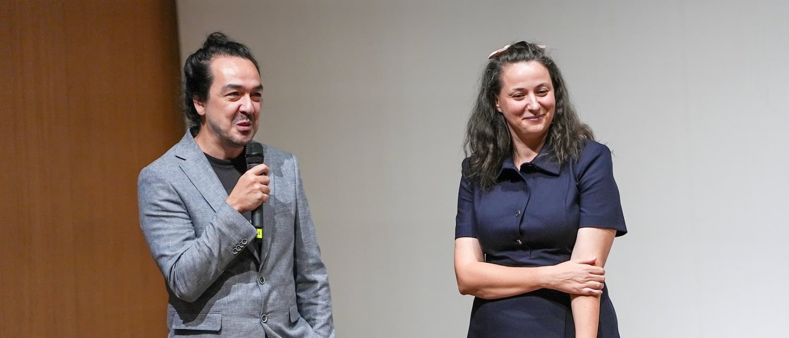 Directors Alkan Avcıoğlu, holding a microphone, and Gizem Avcıoğlu (Vikki Bardot) standing before the screen at the Antalya Golden Orange Q&A for A Woman Asleep
