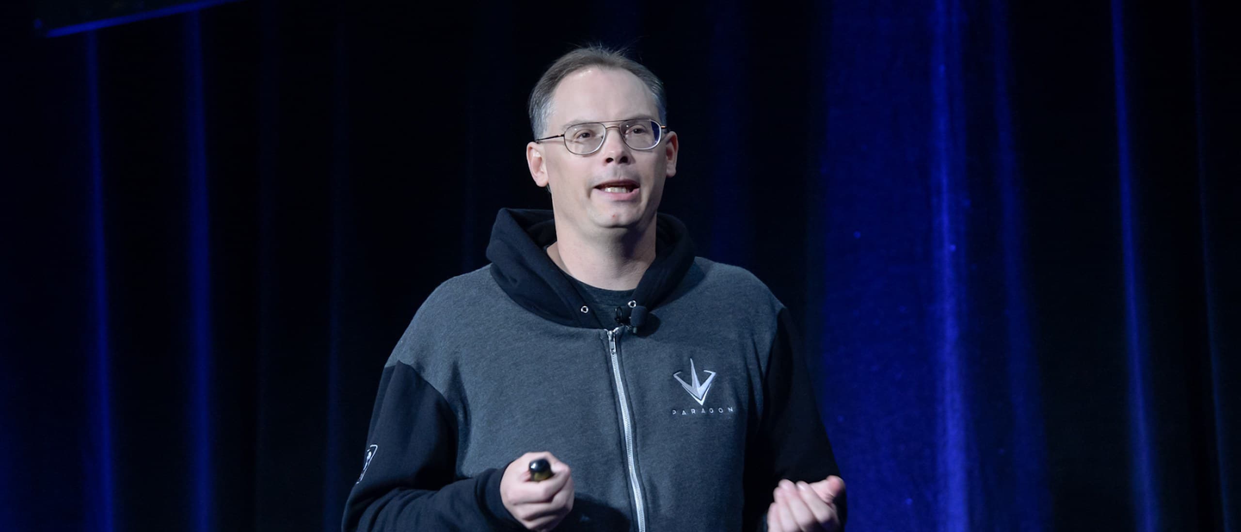 Epic Games CEO Tim Sweeney speaking on stage in front of a dark blue curtain at the Game Developers Conference in 2016
