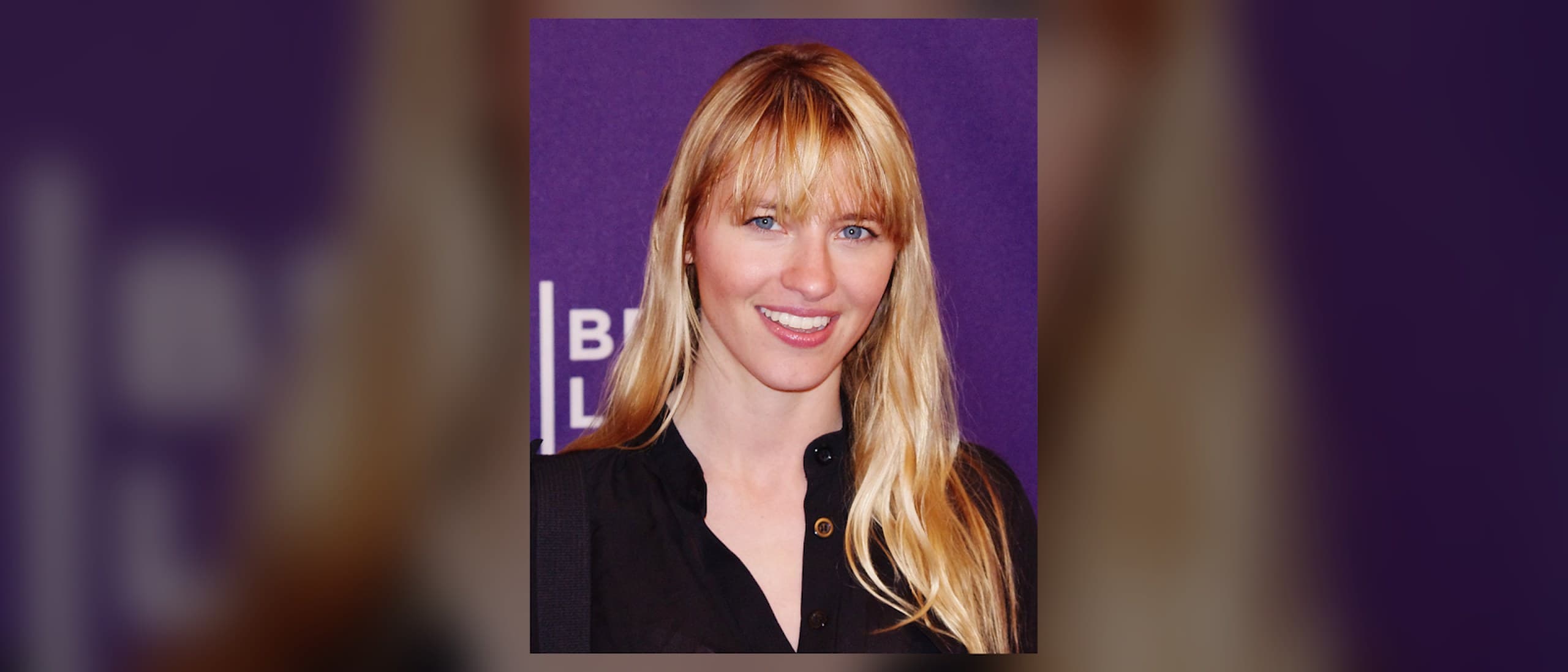 Model Alliance founder Sara Ziff smiling in front of a purple Tribeca Film Festival backdrop, long blonde hair and a black shirt