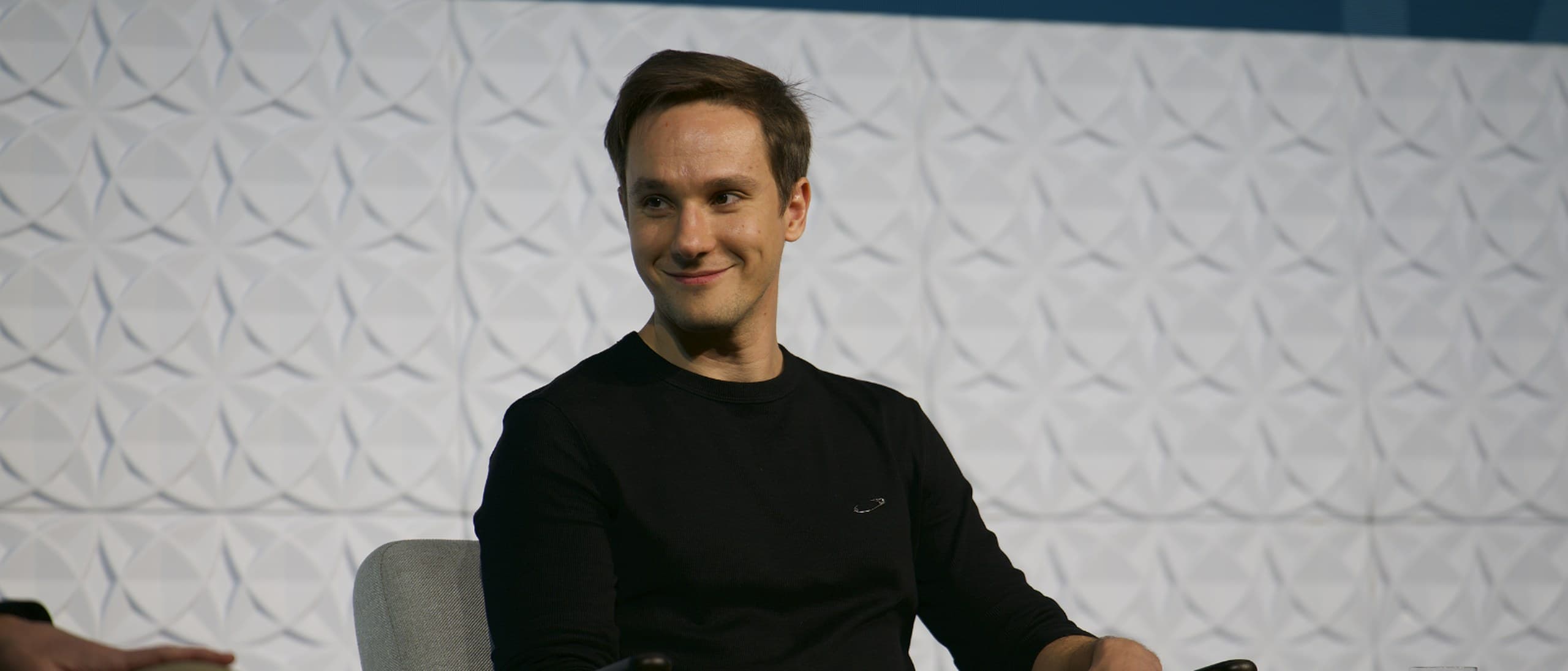 Bogdan Nesvit, co-founder and co-CEO of Holywater Tech, smiling in a chair on a conference stage holding a microphone