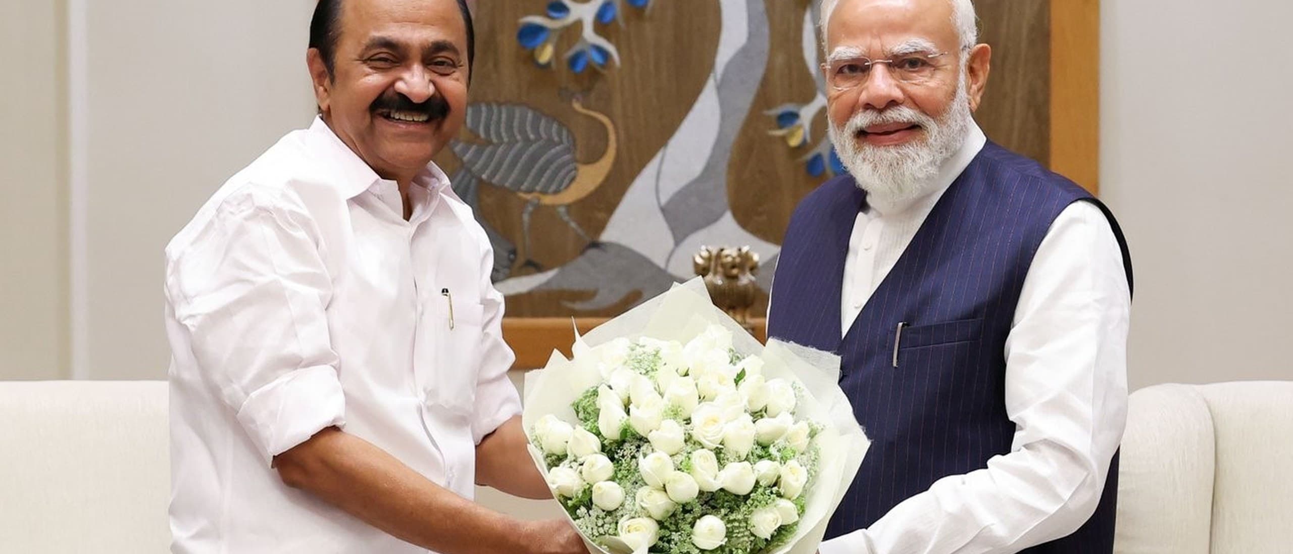 Kerala Chief Minister V D Satheesan, in a white shirt and mundu, hands a bouquet of white roses to Prime Minister Narendra Modi in New Delhi