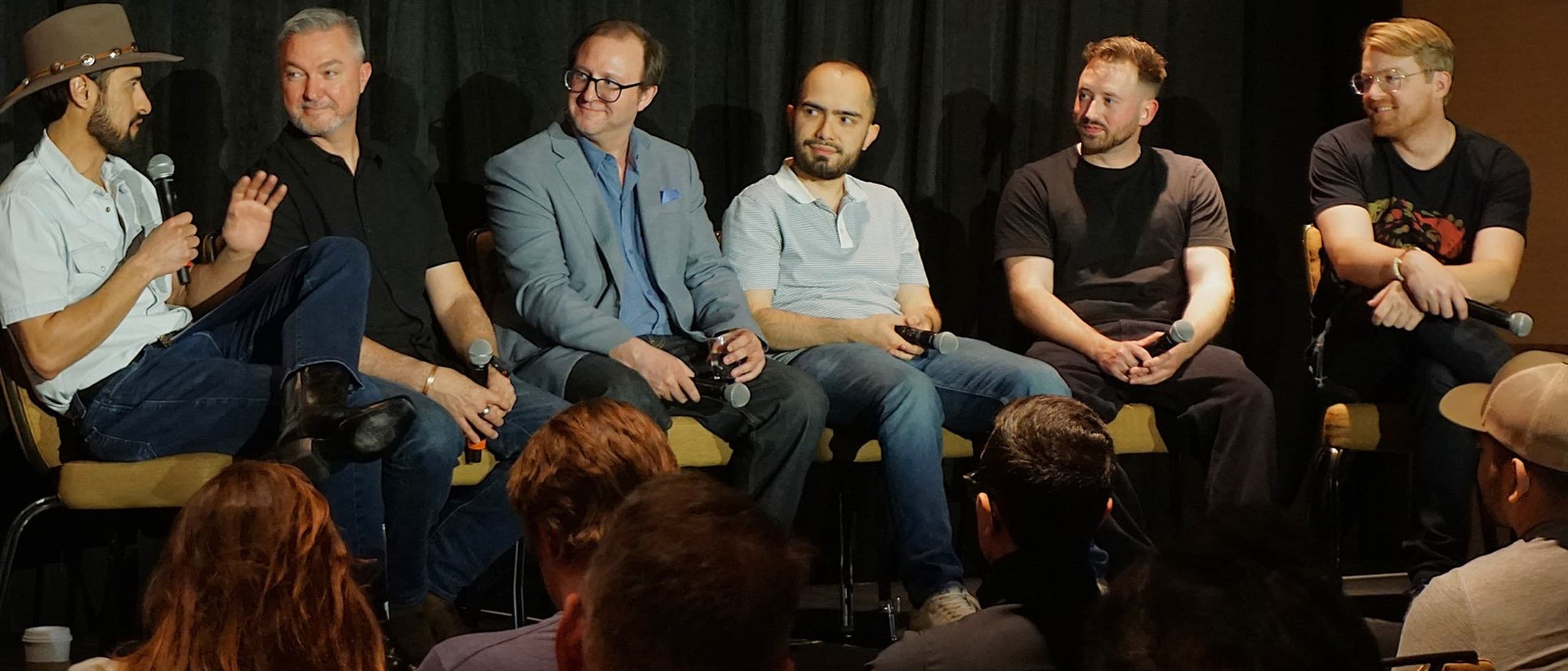 Six filmmakers seated in a row on stage with microphones, talking to an audience during a panel at the first Austin AI Film Festival in March 2025