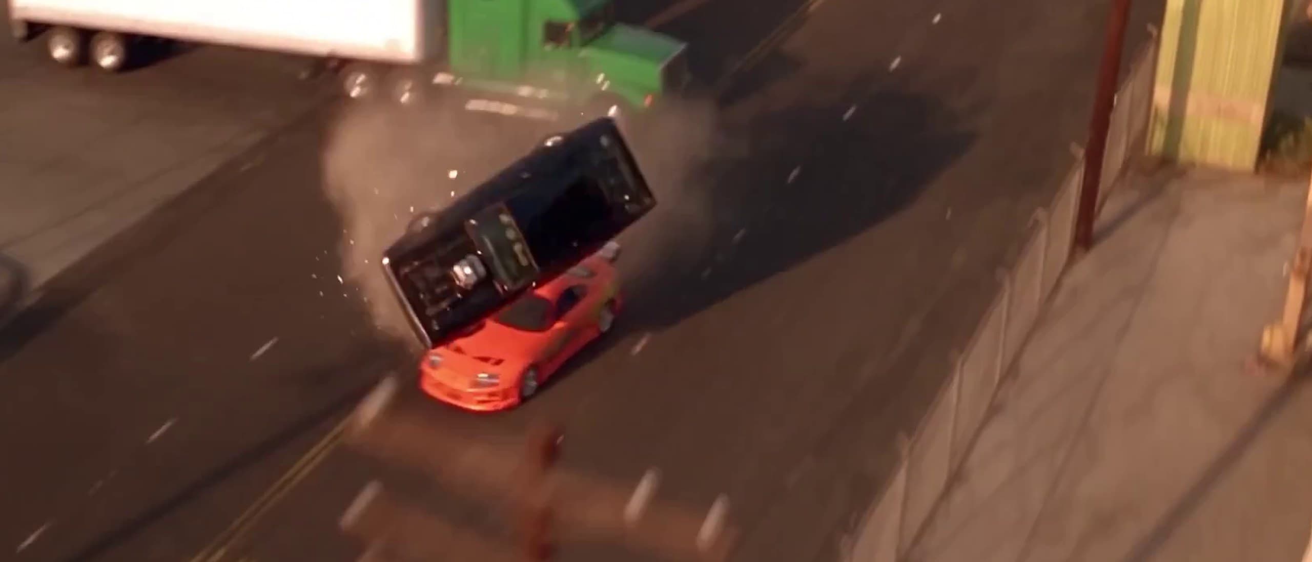Aerial view of a black Dodge Charger flipping through the air over an orange Toyota Supra beside a green-cab semi truck on an industrial road